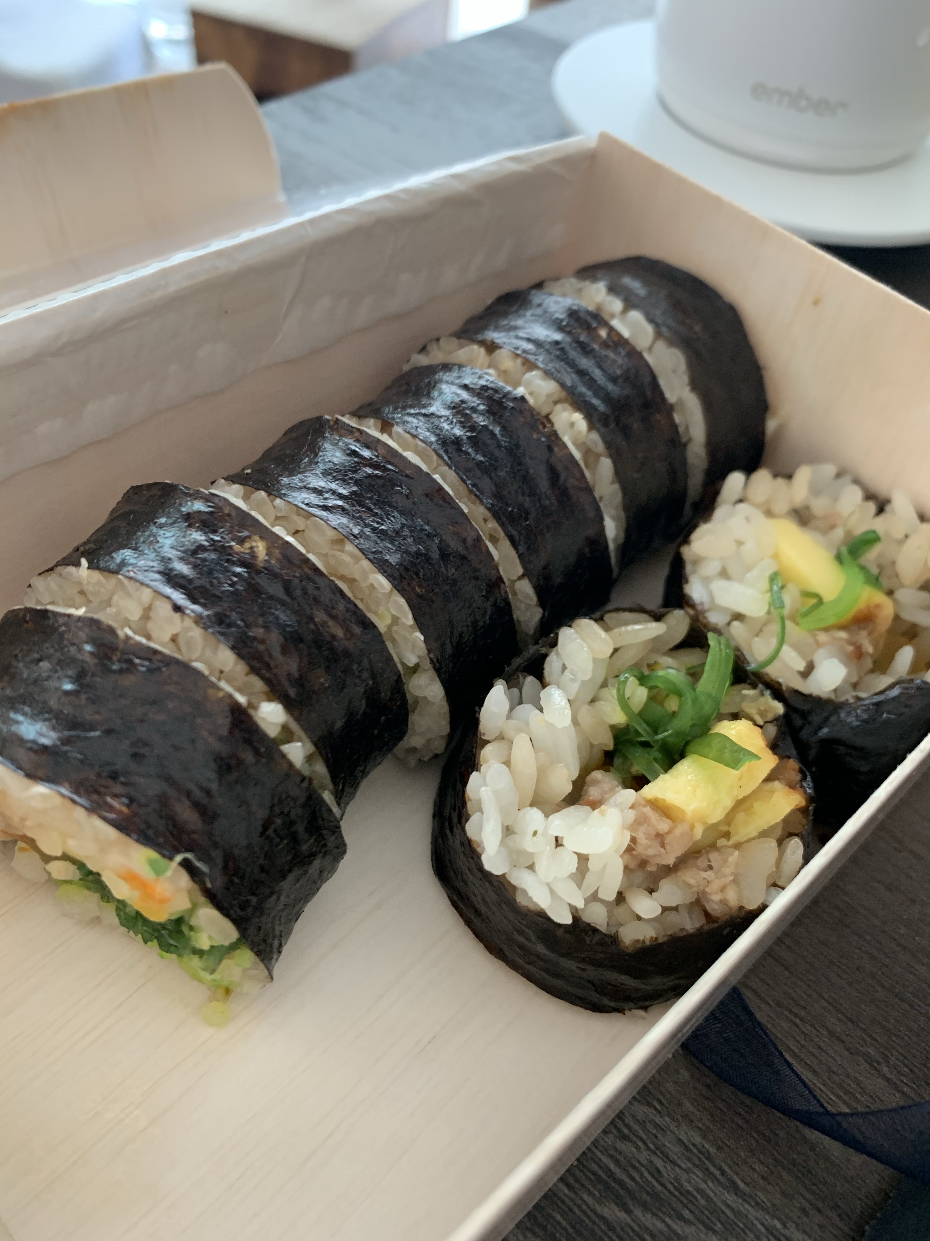 Korean kimbap in a wooden box, filled with egg, green onion, and other vegetables not visible.