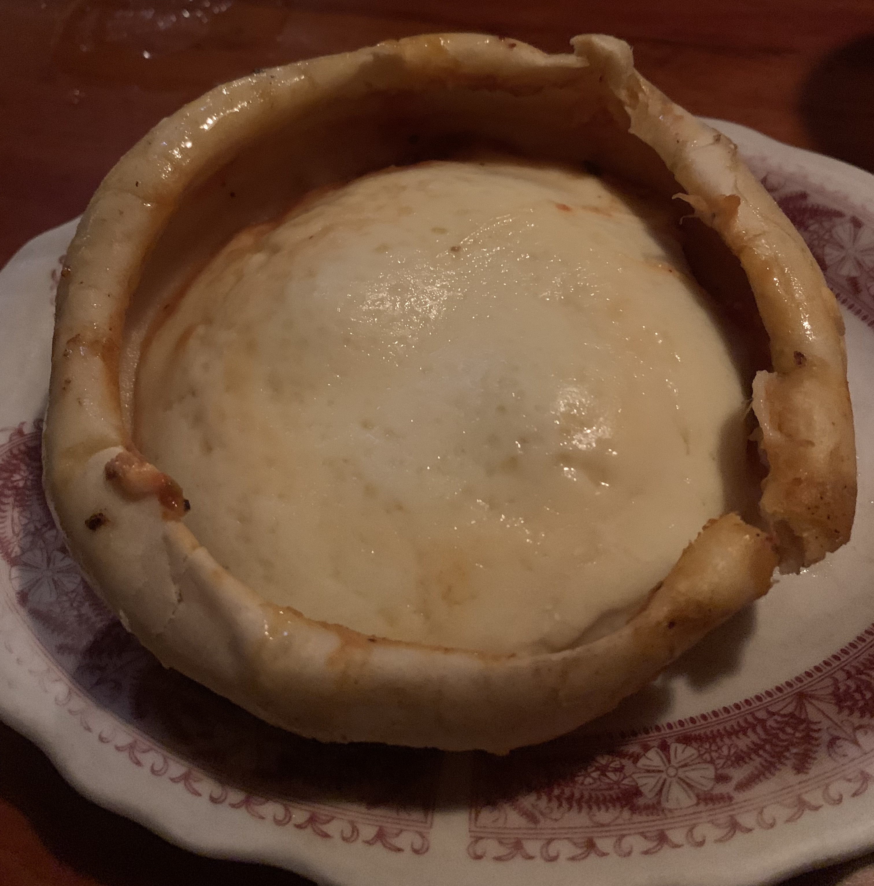 Personal-sized deep-dish style pizza: a smooth, pale bread dough filled with a dome of mozzarella. No toppings or tomato sauce are visible.