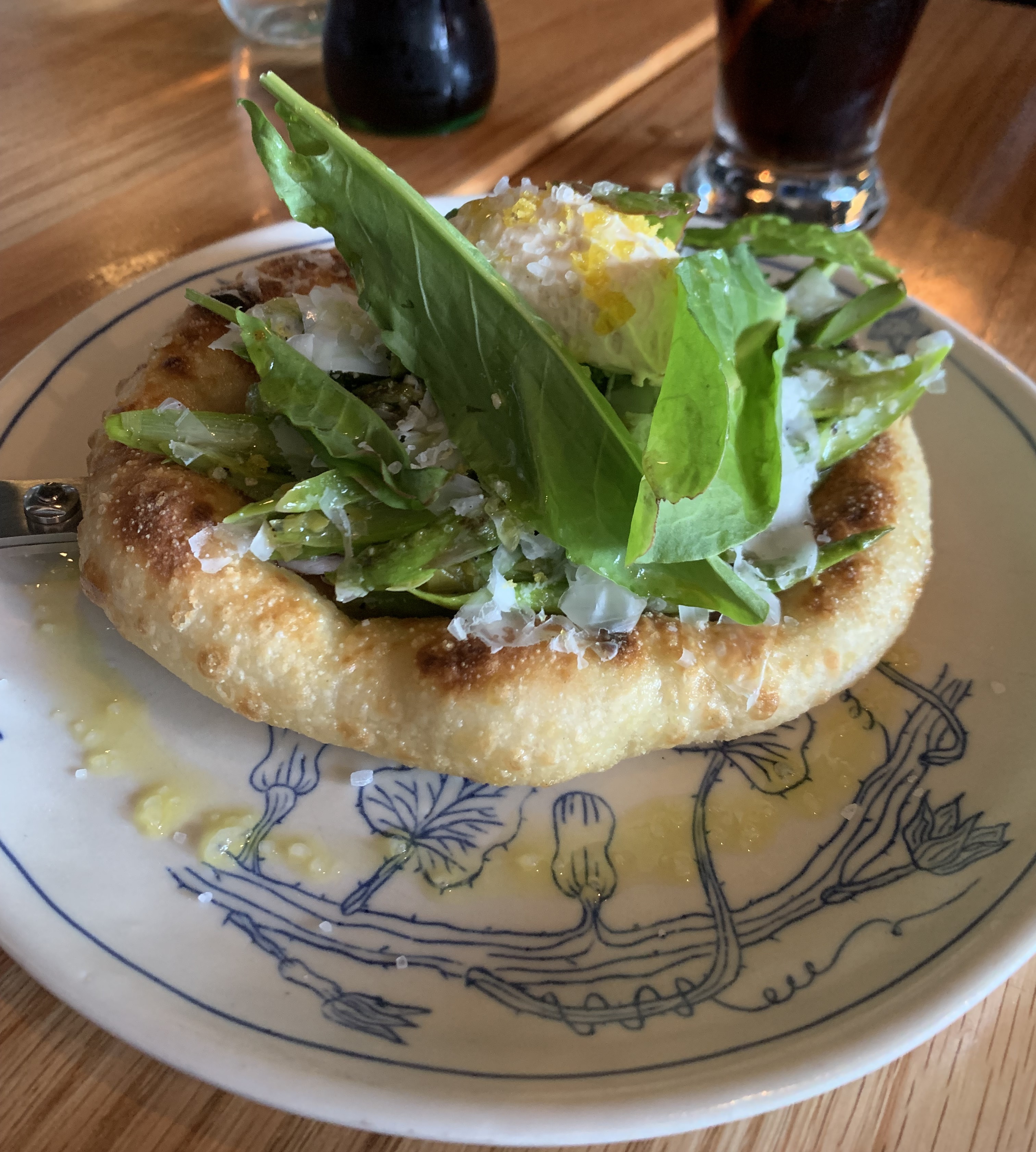 Flatbread with a ton of greens on top, a thin ring of butter around it, and a quenelle of yellow-ish custard