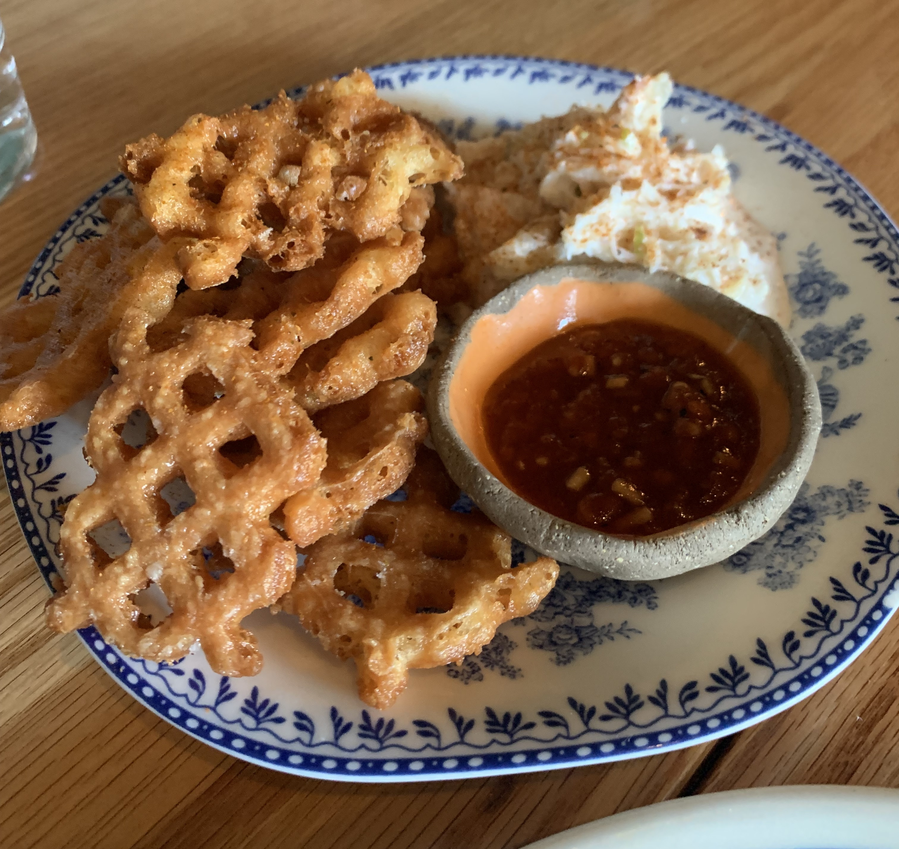 Big waffle fries with a very consistent shape served next to a crab salad and a small bowl of deep red cocktail sauce