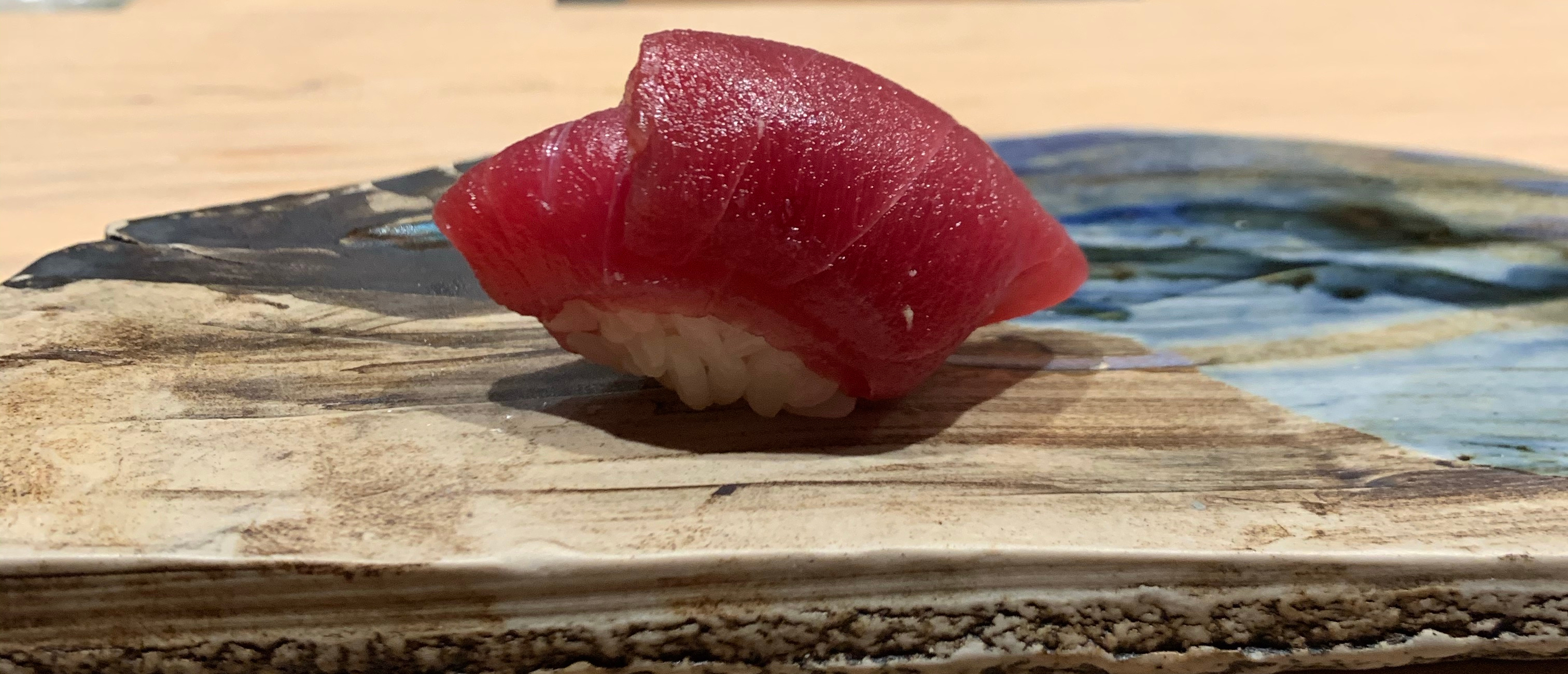 One piece of nigiri sushi, with a deep red fish