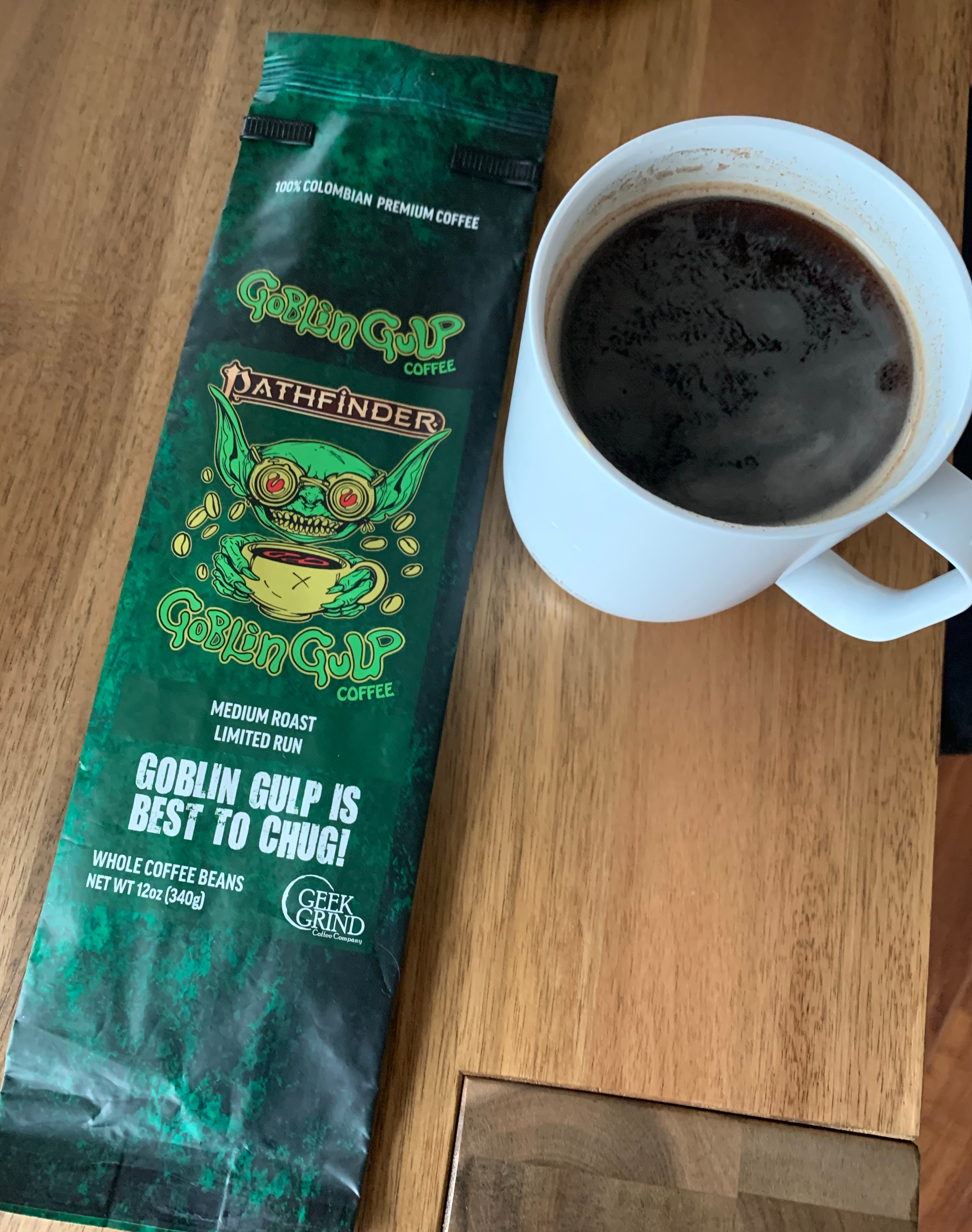 Mug of coffee next to an emty bag of Geek Grind's Goblin Gulp medium roast Colombian coffee
