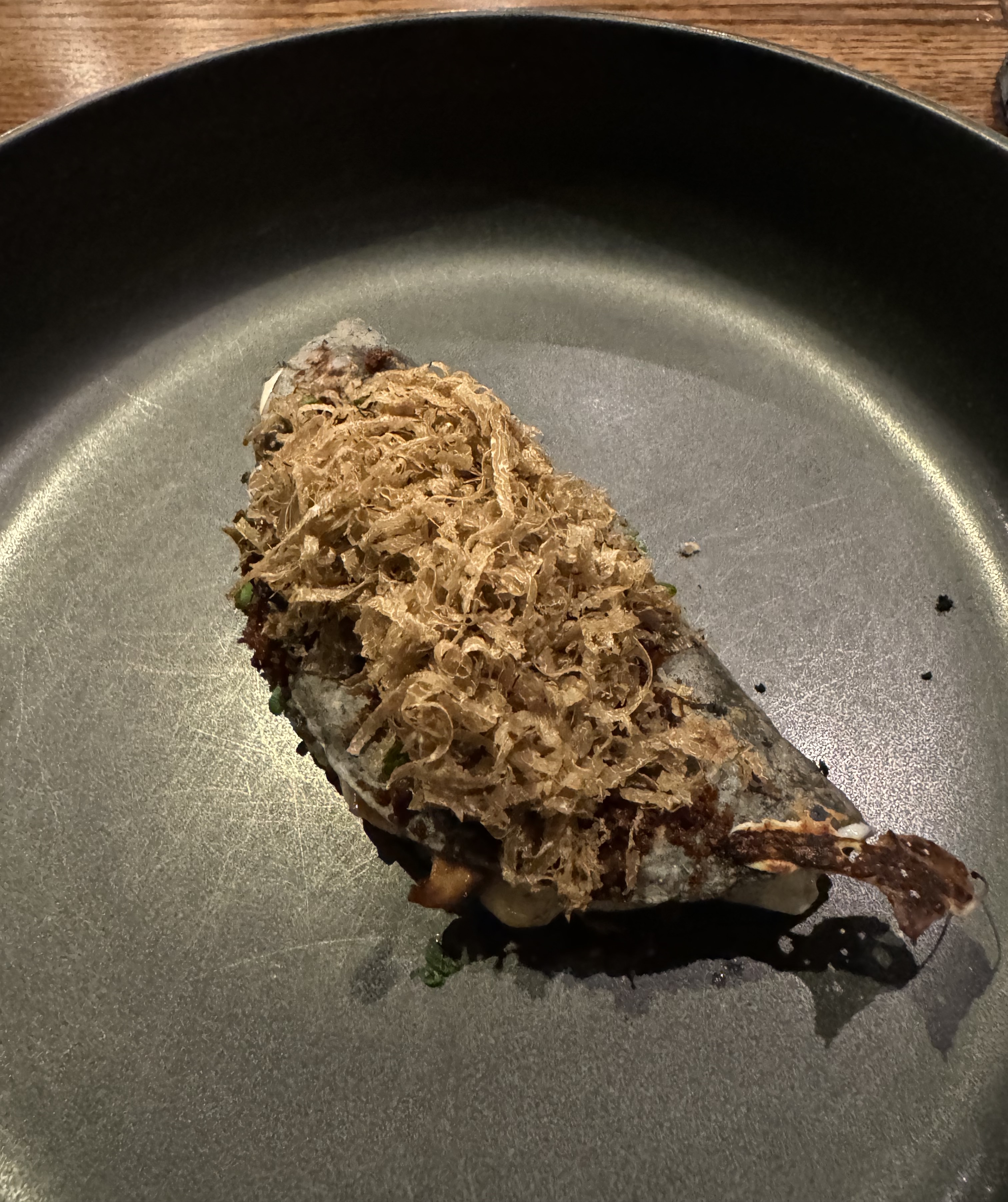 Blue corn tortilla folded over itself, stuffed with cheese and topped with a generous heap of freshly-shared black truffle, served on a black plate.