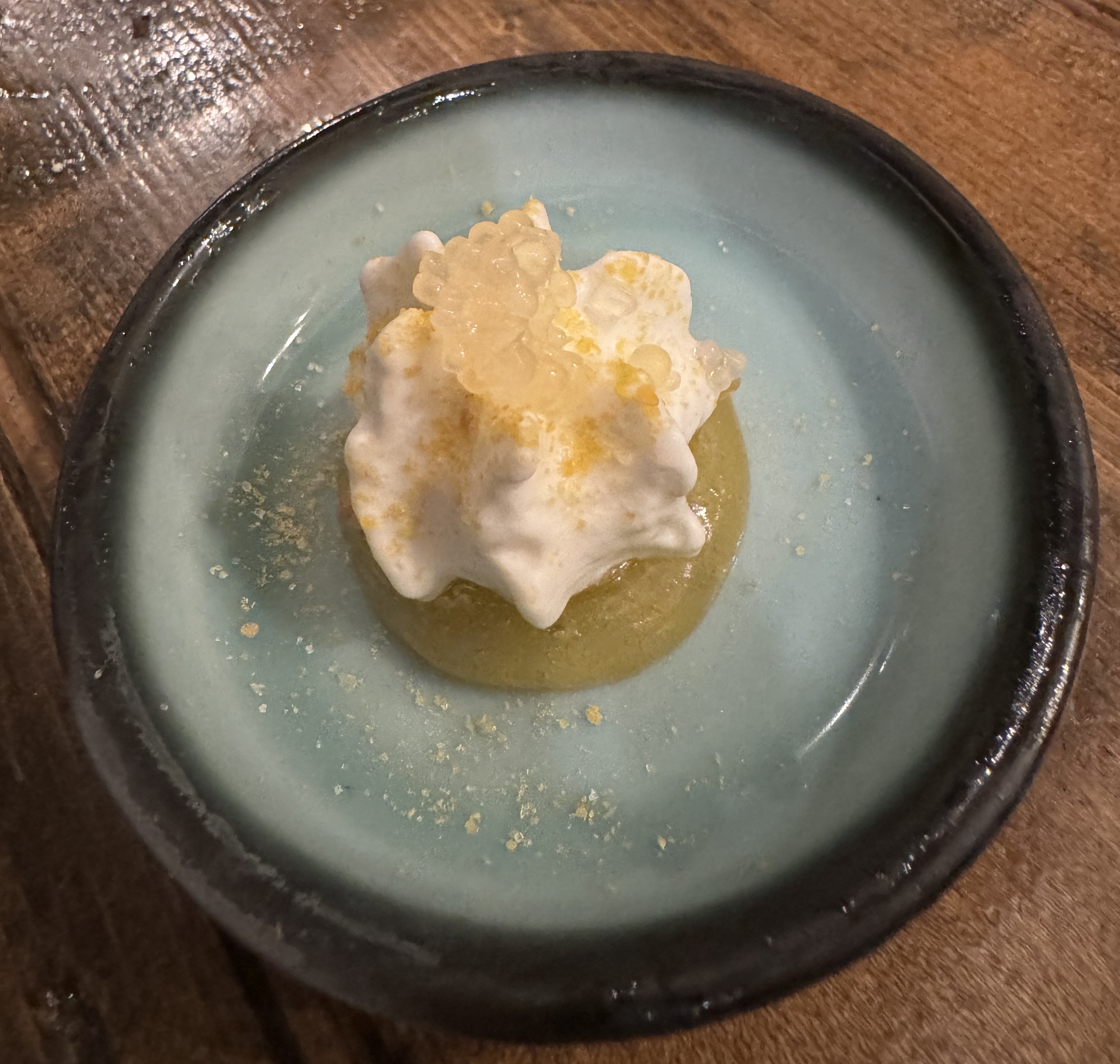 Fluffy whipped yogurt atop a disc of yellow gel, with dots of finger lime on top as a garnish.