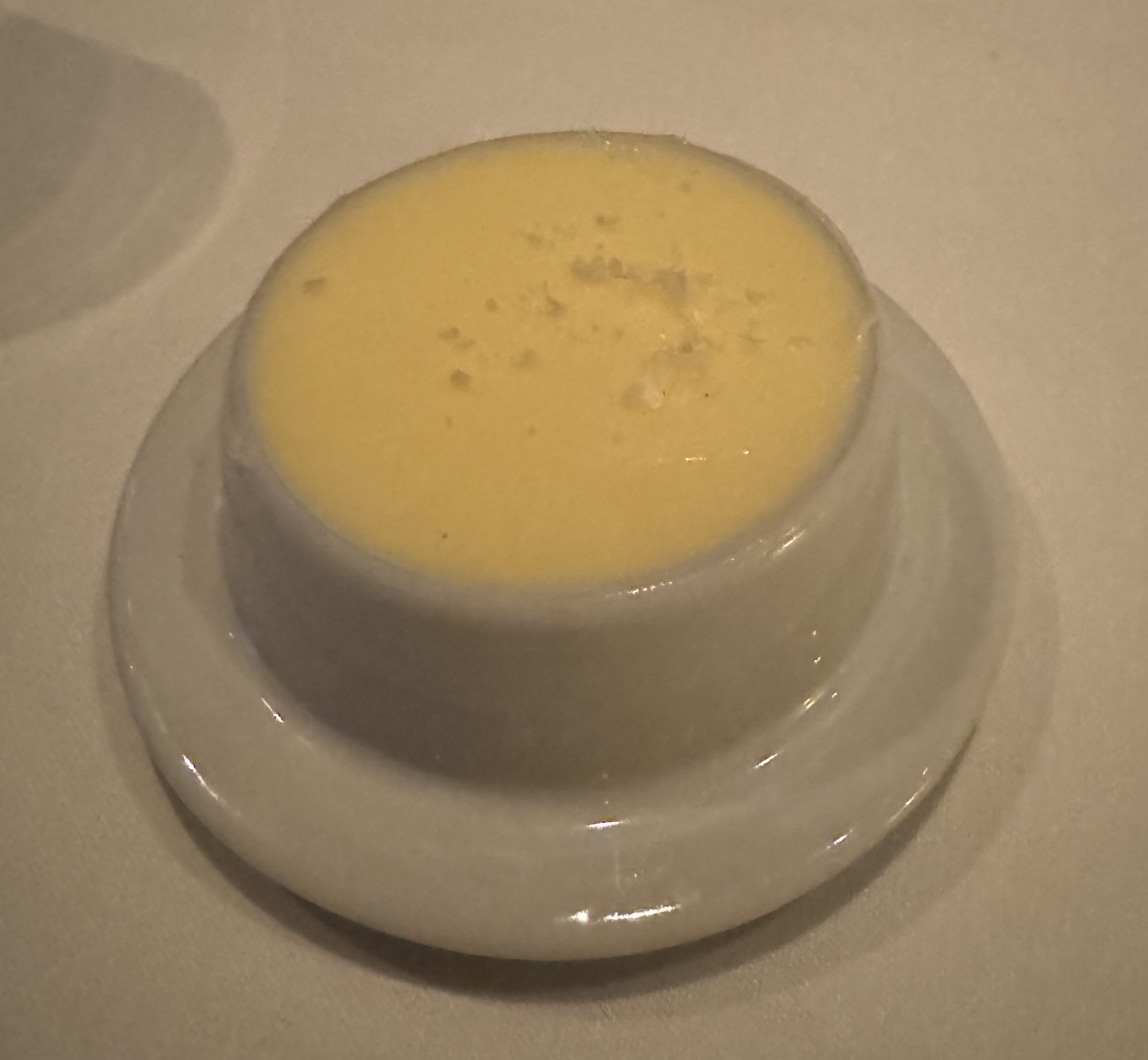 Butter dish with light-yellow butter. There is some flaky salt on top.