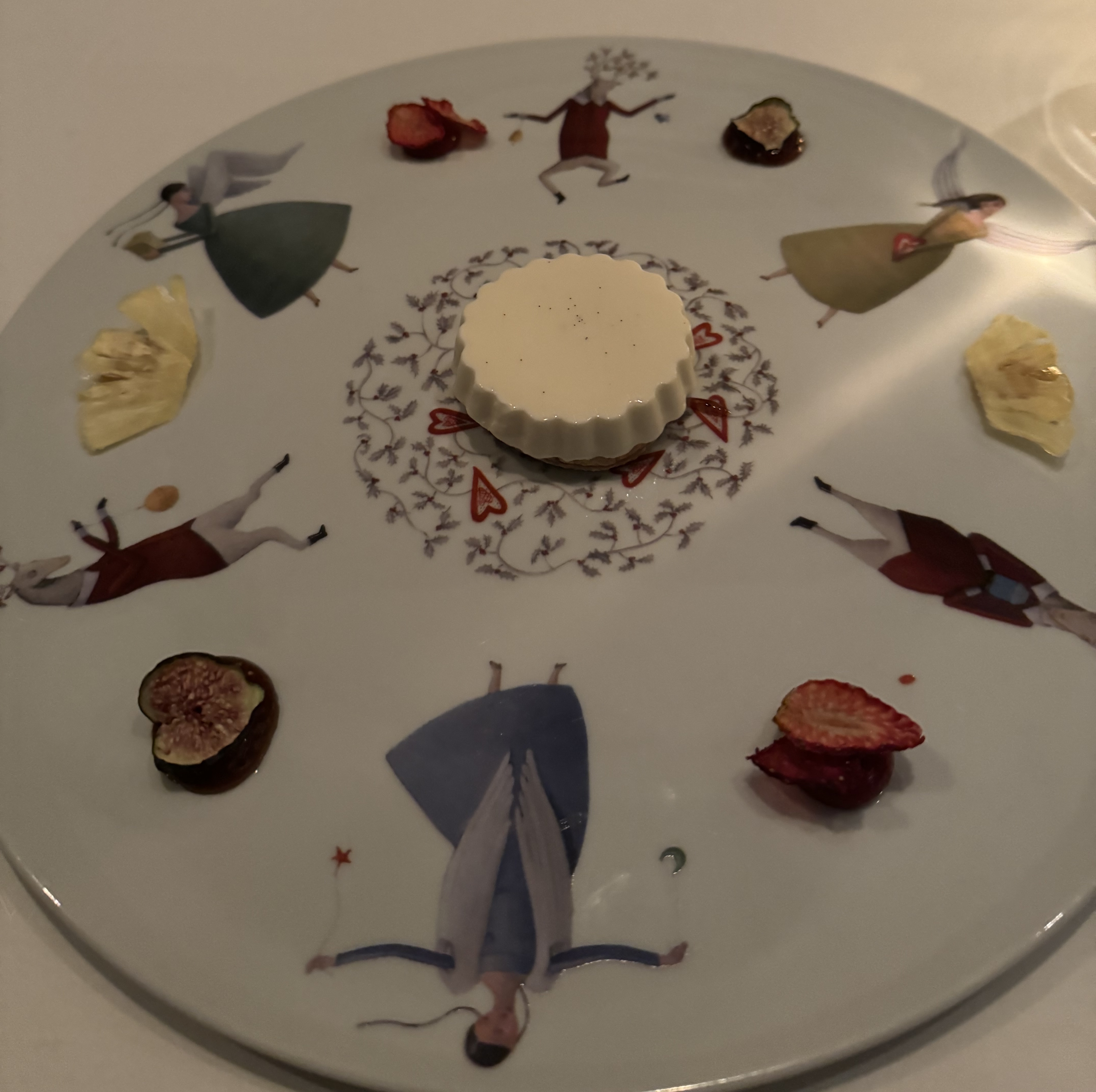 Large dinner plate with characters around the edge. There is a fluted custard in the center. Between the characters, there are alternating freeze-dried strawberries, figs, and pineapples with sauce of the corresponding colour under them.