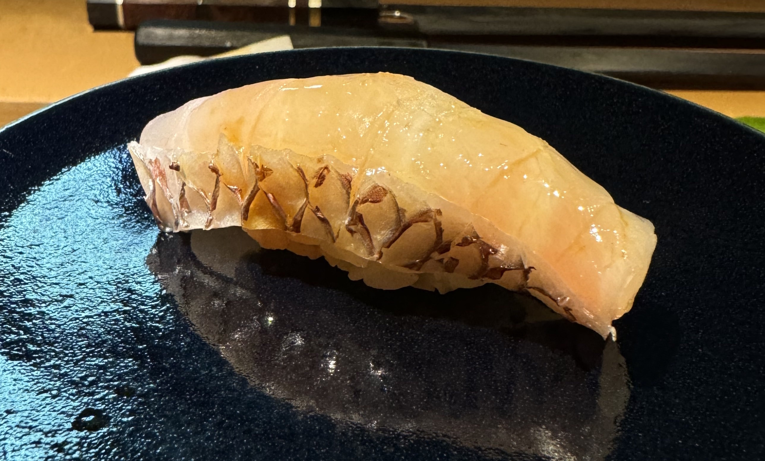 Large white fish on top of barely-visible rice. The fish had some slight banding. The side has the skin attached; the skin is white, with a cross-hitched pattern where the scales were.