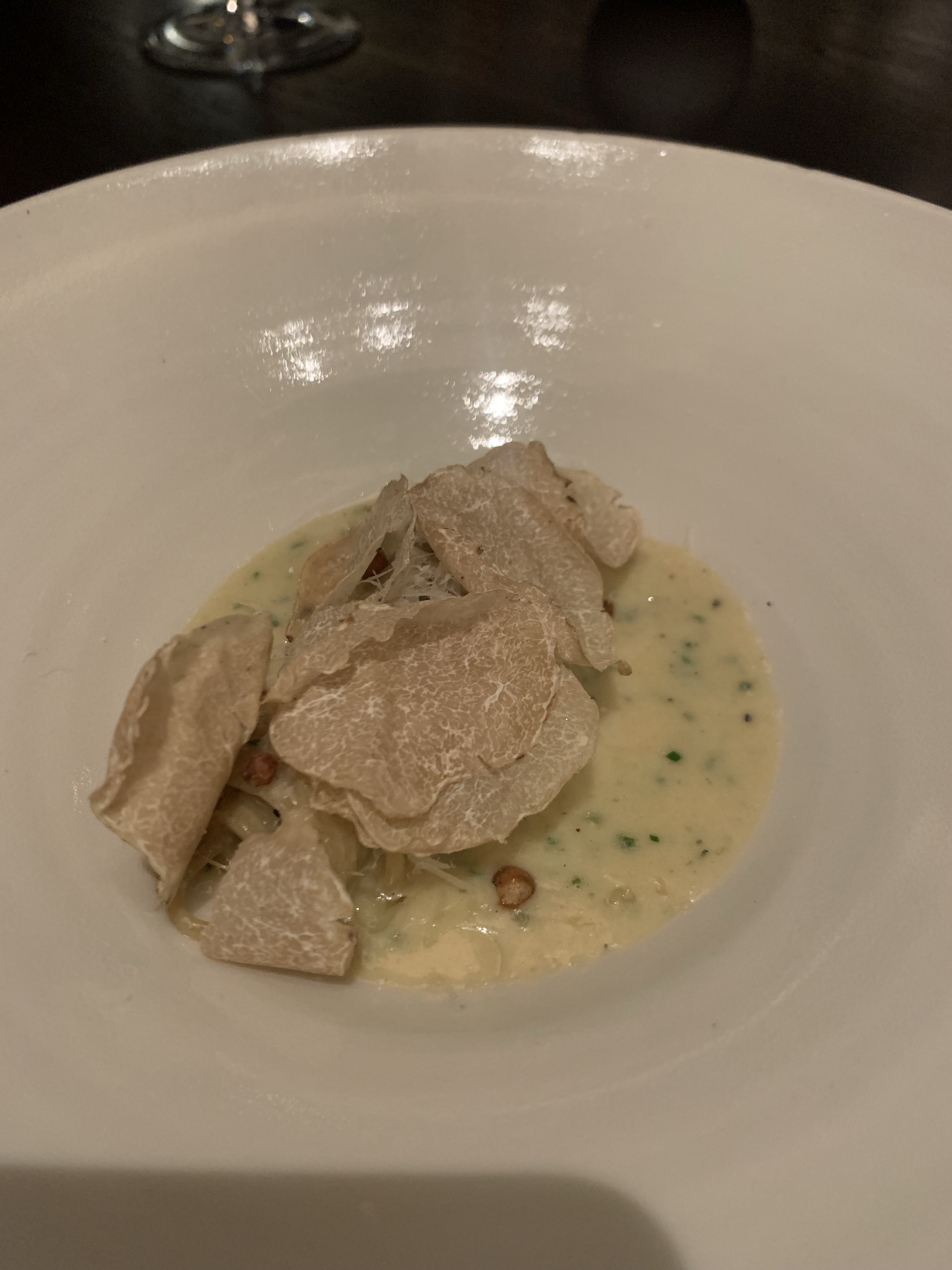 Loads of shaved white truffles on top of a white sauce