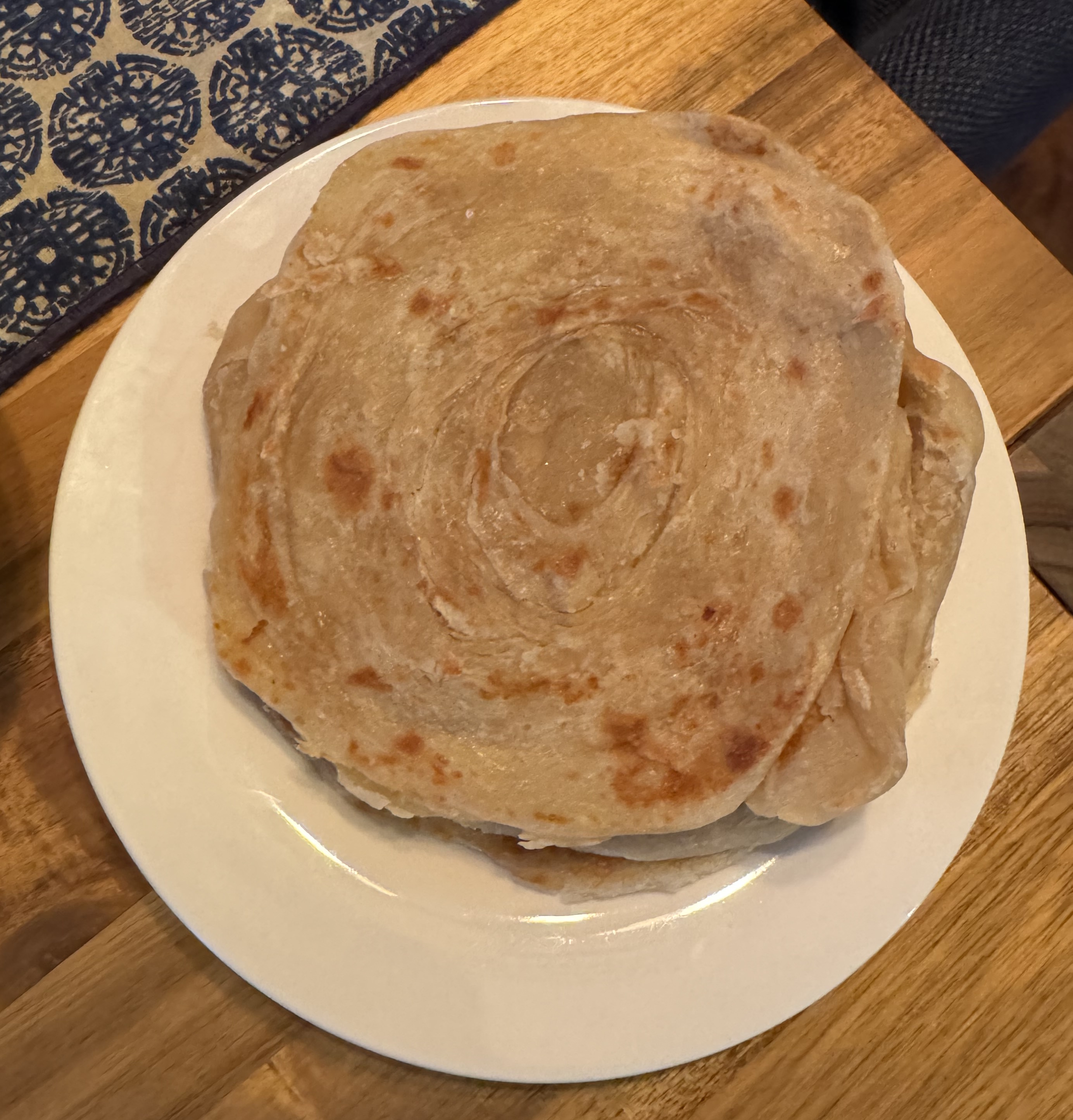 A plate with a stack of flat breads. The breads are lightly browned, and you can see they're a flattened spiral of dough, creating natural layering.