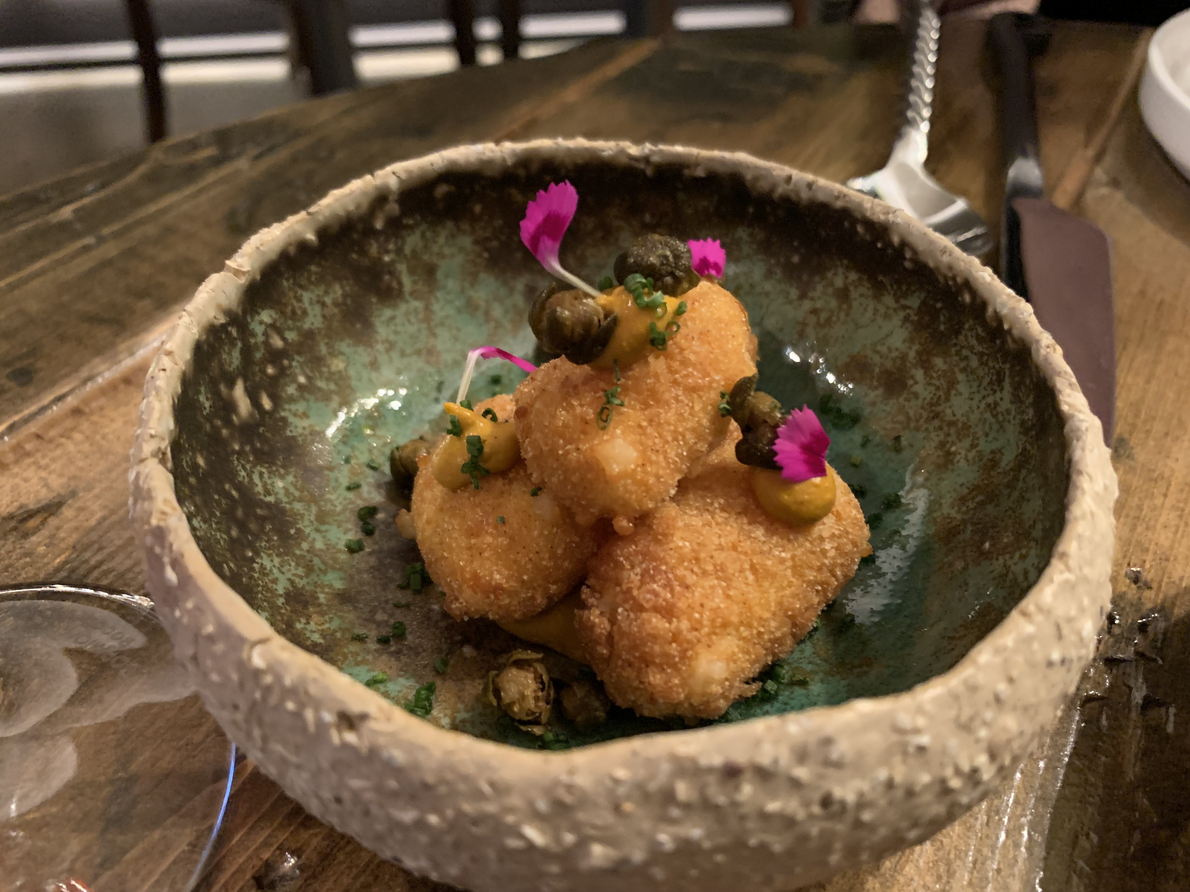 Stack of fried cheese curds in a bowl, with dollops of orange sauce and capers